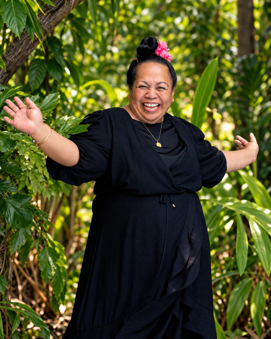 Vienna Senima Richards laughing with her arms open in a tropical garden